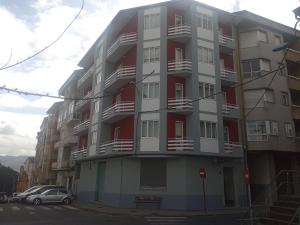 un edificio de apartamentos alto con balcones rojos y blancos en Hostal Outarelo, en Ourense