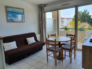 sala de estar con sofá, mesa y sillas en Appartement Golf et Nivelle avec piscine et parking en Ciboure