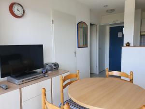 a living room with a wooden table and a tv at Appartement Golf et Nivelle avec piscine et parking in Ciboure