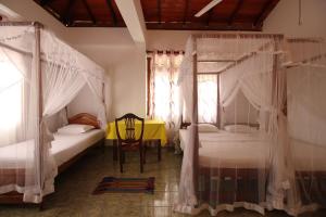 a bedroom with two beds and a table and a chair at Ritas Hotel in Hikkaduwa