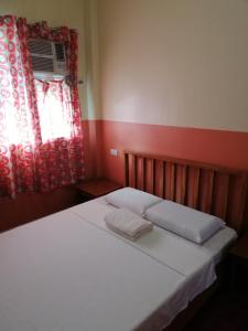 a bedroom with a bed with white sheets and a window at ISLET VIEW Pension House ( Formerly Island View Pension House ) in Oslob