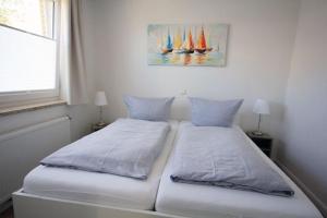 ein Schlafzimmer mit 2 Betten und einem Gemälde von Segelbooten in der Unterkunft Große Ferienwohnung 3 mit Meerblick und Strandkorb im Haus Seeluft Duhnen in Cuxhaven