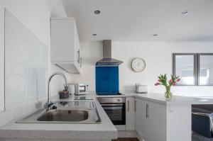 cocina blanca con fregadero y reloj en Sea Front Apartment, en Saltburn-by-the-Sea