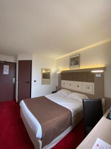 una camera con un grande letto e un tappeto rosso di Kimotel Epône-Flins a Épône