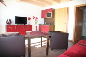 eine Küche mit einem Esstisch und roten Schränken in der Unterkunft Ute's Pension in Georgenberg
