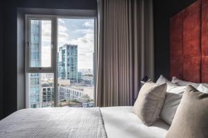 a bedroom with a large window overlooking a city at The Gate London City in London