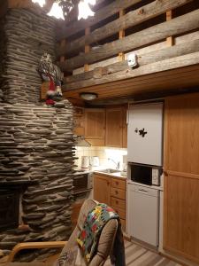 a kitchen with a stone wall and a white refrigerator at Levi Pikkurakka 4A4 in Kittilä