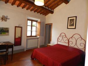 1 dormitorio con cama roja, mesa y ventana en Angolo Alla Fortezza - Gigliola Contucci, en Montepulciano