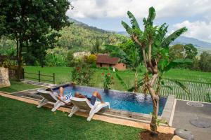 two people laying in chairs next to a swimming pool at Mandhasativa Homestay in Singaraja