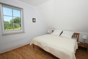 ein weißes Schlafzimmer mit einem Bett und einem Fenster in der Unterkunft Ostseehaus Odin Doppelhaushälfte in Wiek auf Rügen 