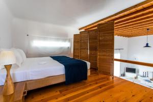 a bedroom with a large bed and wooden floors at Sunset Villa Iza in Agios Ioannis Mykonos +35 photos