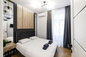 a bedroom with a white bed and a large window at Royal apartment on Hmelnytskogo 37 in Lviv