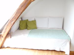 een wit bed met groene kussens in een kamer bij Au Moulin Géant in Rochefort-sur-Loire