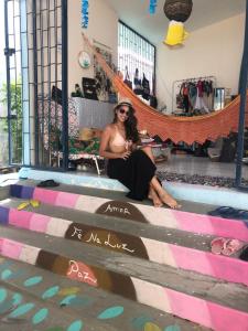 a woman sitting on the steps of a store at Hostel das Canárias in Natal