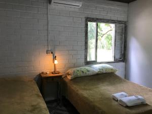 um quarto com duas camas, uma janela e um candeeiro em Sitio dos Rochedos em Ivoti