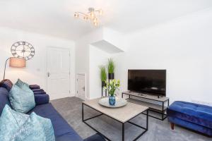 a living room with a blue couch and a tv at Knavesmire Mews 3 bedrooms-Free parking in York