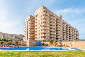 un gran edificio de apartamentos con piscina frente a él en Vacaciones Oromarina Jardines del Mar en Oropesa del Mar