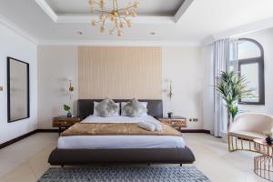 a bedroom with a large bed and a chandelier at Stella Stays Gorgeous 5 BDR Palm Villa Beach Private Pool in Dubai