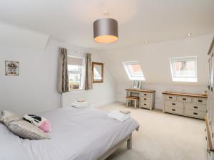 um quarto com uma grande cama branca e 2 janelas em 49 Ulwell Road em Swanage