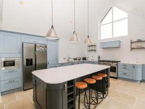 uma cozinha com armários azuis e uma ilha branca com bancos em 49 Ulwell Road em Swanage