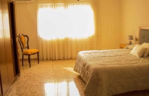um quarto com uma cama, uma cadeira e uma janela em CAL SAMARRA em L'Ametlla de Mar