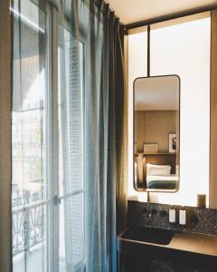 a bathroom with a sink, mirror, and window at Hôtel National Des Arts et Métiers in Paris