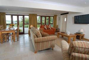 a living room with couches and a dining room at Sheepscombe Byre in Snowshill