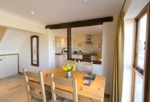 a kitchen and dining room with a wooden table and chairs at Sheepscombe Byre in Snowshill