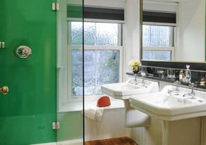 a green and white bathroom with two sinks and a window at The Dunraven, Adare in Adare