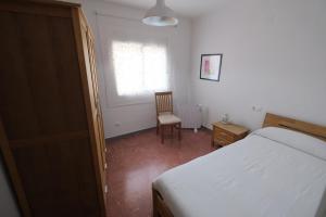 a bedroom with a bed and a chair and a window at Apartament Tarracoliva in Tarragona