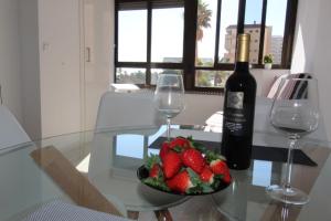 una mesa de cristal con un plato de fresas y una botella de vino en Przytulny Apartament z widokiem na morze !!!!!, en La Mata