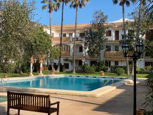 a swimming pool in front of a building with a bench at Apartamento EL PATIO V in Denia