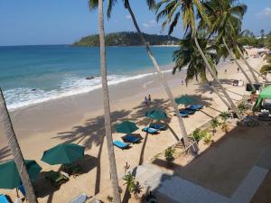 a beach with chairs and umbrellas and the ocean at Sunset Beach Hotel in Mirissa