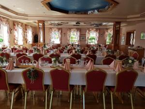 un salón de banquetes con mesas blancas y sillas rojas en Gasthaus Neue Mühle en Kassel