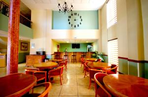 a restaurant with wooden tables and chairs and a clock at Hotel Consulado Inn in Ciudad Juárez