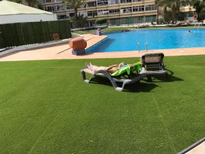 a person laying on a lawn chair next to a swimming pool at residence los molinos in Maspalomas