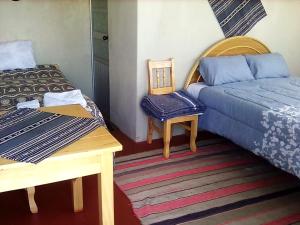 Cette chambre comprend deux lits, une table et une chaise. dans l'établissement Alberto homestay taypi qamaña establo, à Juliaca