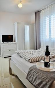 a white bedroom with a bed with a bottle of wine on a tray at IWONA Pokoje Apartamenty in Karwia