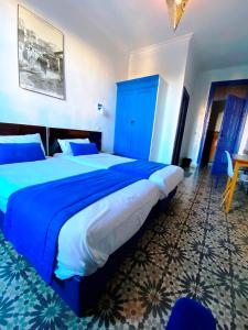 a bedroom with a large bed with blue sheets at Hôtel Central in Casablanca