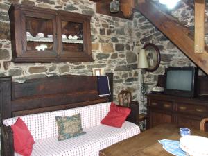 a living room with a couch and a tv and a stone wall at Casa Trallera in Colinas del Campo de Martín Moro