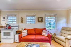 a living room with a red couch and a chair at Woodland Cottage by the Sea in Yachats