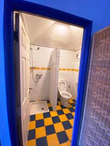 ein Badezimmer mit einem WC und einem gelben und schwarzen karierten Boden in der Unterkunft Hôtel Central in Casablanca