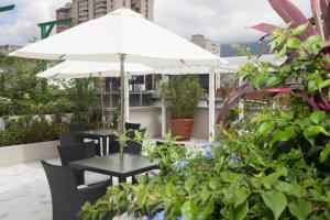 a table and chairs with an umbrella on a rooftop at Waldorf Hotel in Caracas