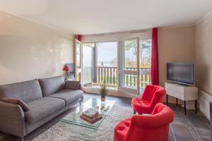 een woonkamer met een bank, 2 stoelen en een televisie bij Charming and calm flat with balcony and parking in Trouville - Welkeys in Trouville-sur-Mer