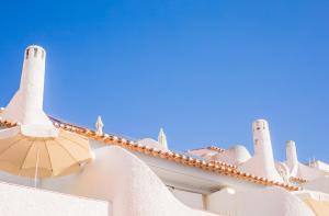 a white building with turrets and an umbrella at Apartamentos Borda D´Agua in Albufeira