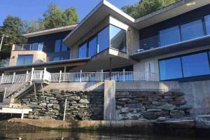 a large house with a stone wall at Panoramaresort in Hardangerfjorden With boat to rent - leilighet i sjøkanten ved Hardangerfjorden for 7 personer NEW sauna from desember 2023 in Øystese