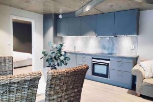 a kitchen with blue cabinets and wicker chairs at Panoramaresort in Hardangerfjorden With boat to rent - leilighet i sjøkanten ved Hardangerfjorden for 7 personer NEW sauna from desember 2023 in Øystese