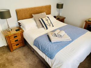 - une chambre avec un lit, des serviettes et 2 lampes dans l'établissement Pinewood B&B, à Saundersfoot