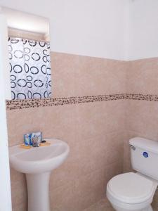 Un baño con un inodoro blanco y un lavabo. en Hospedaje La Ola Azul, en Puerto Chicama