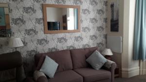 a living room with a brown couch and a mirror at Morwenna Luxury Holiday Apartments in Llandudno